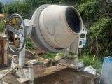 a cement mixer that is sitting on a pile of dirt