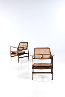 une paire de chaises longues avec des assises en rotin et une table à plateau en verre