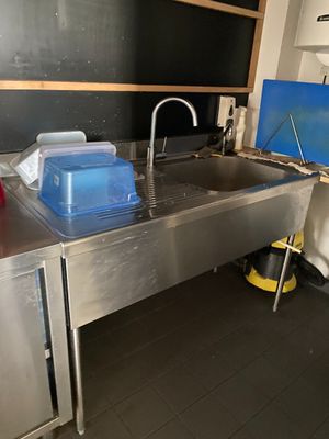 un évier en acier inoxydable dans une cuisine où se trouve un tableau noir accroché au mur