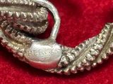a close up of a silver brooch on a red cloth