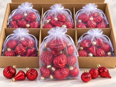 six décorations de Noël rouges dans une boîte, sur fond blanc