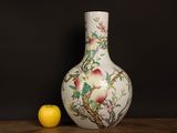 a white vase with flowers and birds on it next to an apple