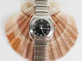 a watch sitting on top of a seashell on a white surface