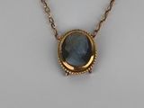 a gold necklace with a blue stone on a chain