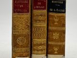 trois vieux livres sont alignés sur une surface blanche