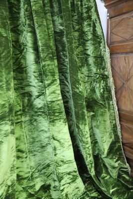 a bed with a green blanket on top of it next to a dresser