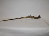 an old brass rifle with a wooden handle on a white surface