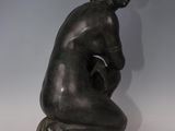 a bronze statue of a man sitting on his knees