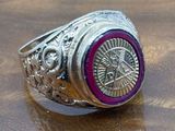 silver ring with a red stone in the center on top of a wooden table