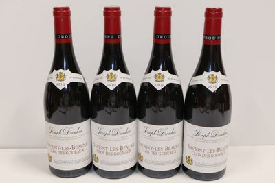 quatre bouteilles de vin rouge sont alignées sur une table