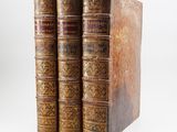three old books sitting on top of each other on a white surface