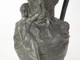 un petit vase orné d'une statuette, posé sur une surface blanche