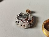 a close up of a watch movement on a table next to a coin