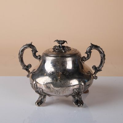 silver plated teapot with dragon handles on a white table