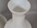 two white vases sitting next to each other on a table