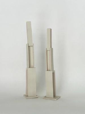 une paire de sculptures en bois blanches posées sur une surface blanche, avec un fond blanc