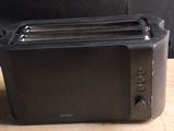 a black toaster sitting on a table next to a person