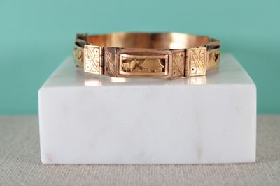 un gros plan d'un bracelet en or posé sur un bloc de marbre