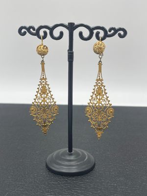 une paire de boucles d'oreilles en or posée sur un support noir