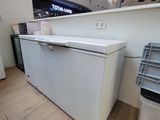 un réfrigérateur blanc posé à côté d'une poubelle dans un magasin