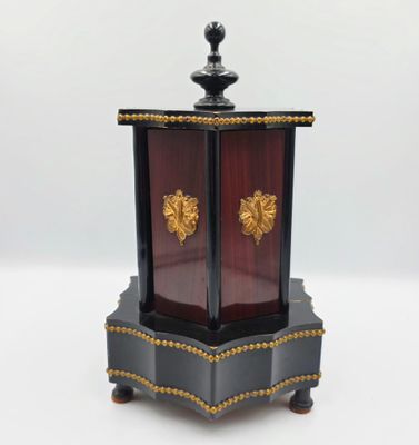 une petite horloge noire et dorée posée sur une surface blanche