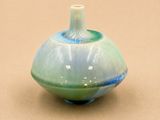 un vase bleu et vert posé sur une surface marron