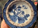a person holding a blue and white plate with a bird on it