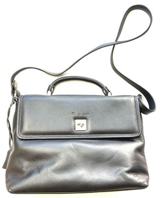 the black purse is sitting on a white surface