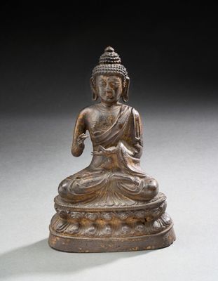 statue en bronze représentant un Bouddha assis sur un socle blanc