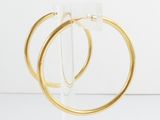 pair of gold hoop earrings on clear acrylic stand