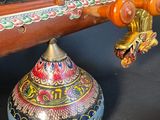 a colorful vase sitting next to a wooden instrument on a black surface