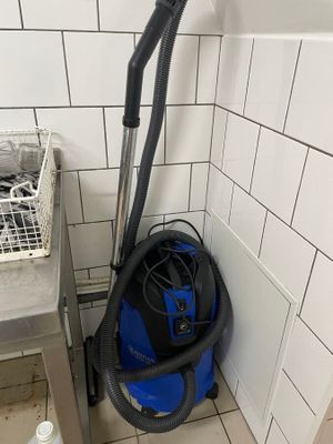 un aspirateur bleu et noir dans un coin de la salle de bains