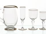 four wine glasses and a pitcher sitting on a table
