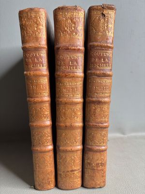 three old books sitting on top of a table next to each other