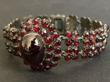 silver ring with garnets and red stones on a black surface
