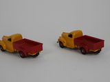 two toy trucks sitting next to each other on a white surface