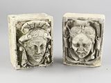 pair of carved stone bookends of a woman ' s face and a man ' s head