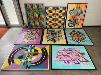 Plusieurs tableaux de formes et de tailles variées sont exposés dans une pièce
