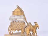 a gold figurine of a horse drawn carriage with a bell on it