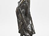 bronze statue of a woman in a coat and hat on a marble base
