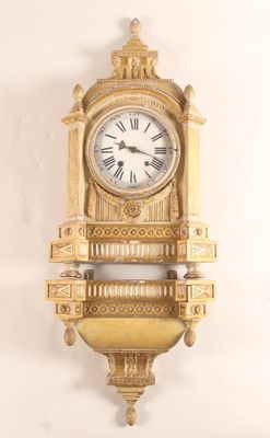 une horloge dorée accrochée au mur, avec des chiffres romains