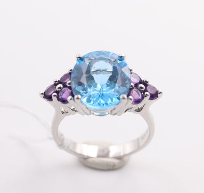 a close up of a ring with a blue topaz and purple amethtites