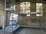 un échafaudage au milieu d'un immeuble, avec une voiture garée à l'arrière-plan