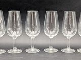 six empty wine glasses lined up in a row on a table