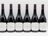 six bottles of wine are lined up on a white surface