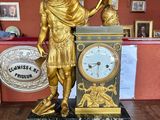 a gold statue of a man holding a clock in a room
