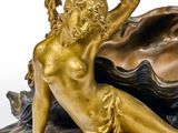 a bronze statue of a woman sitting on a clam shell