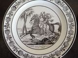 a black and white plate with a picture of a man riding a horse