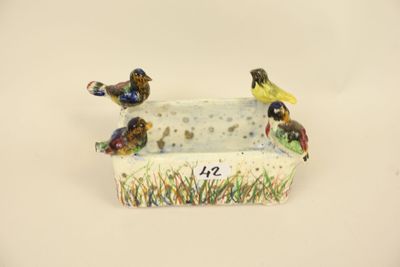 three birds sitting on a planter on a white surface