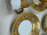 four cups and saucers with gold and blue designs on them